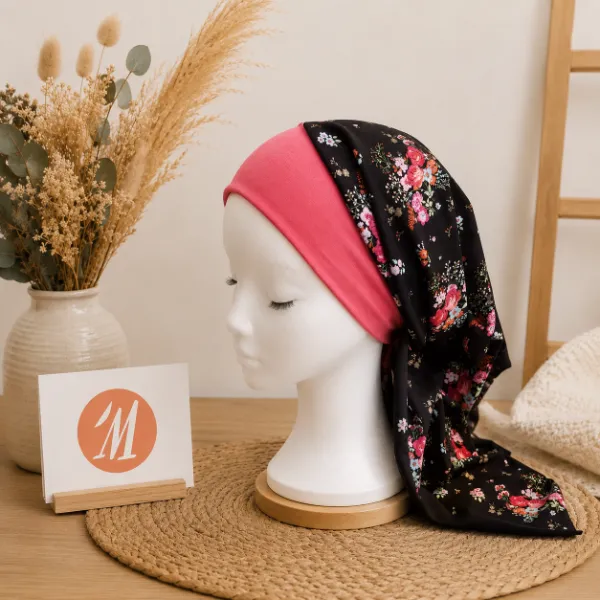 Foulard chimio artisanal noir à fleurs roses avec bandeau rose, confectionné à la main pour apporter confort et élégance pendant la perte de cheveux.